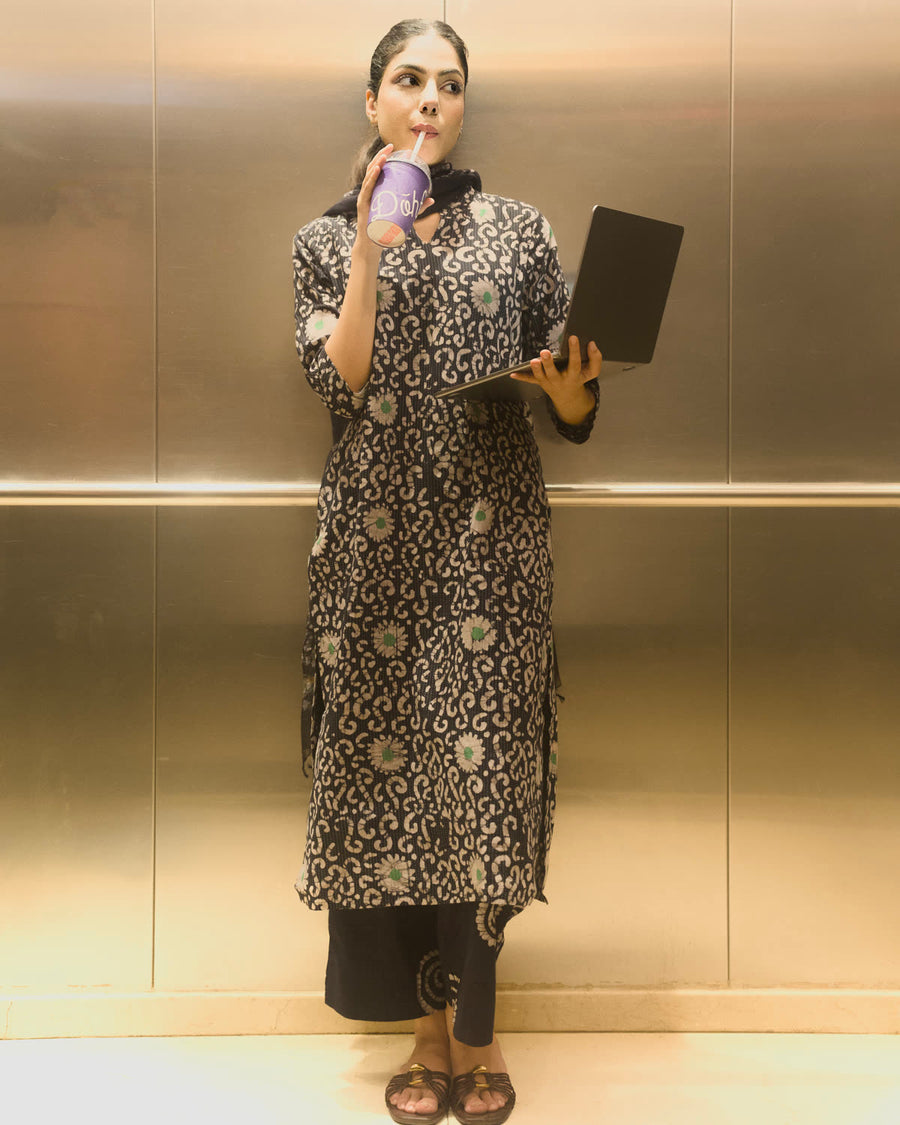Woman in a printed kurta set holding a laptop and coffee