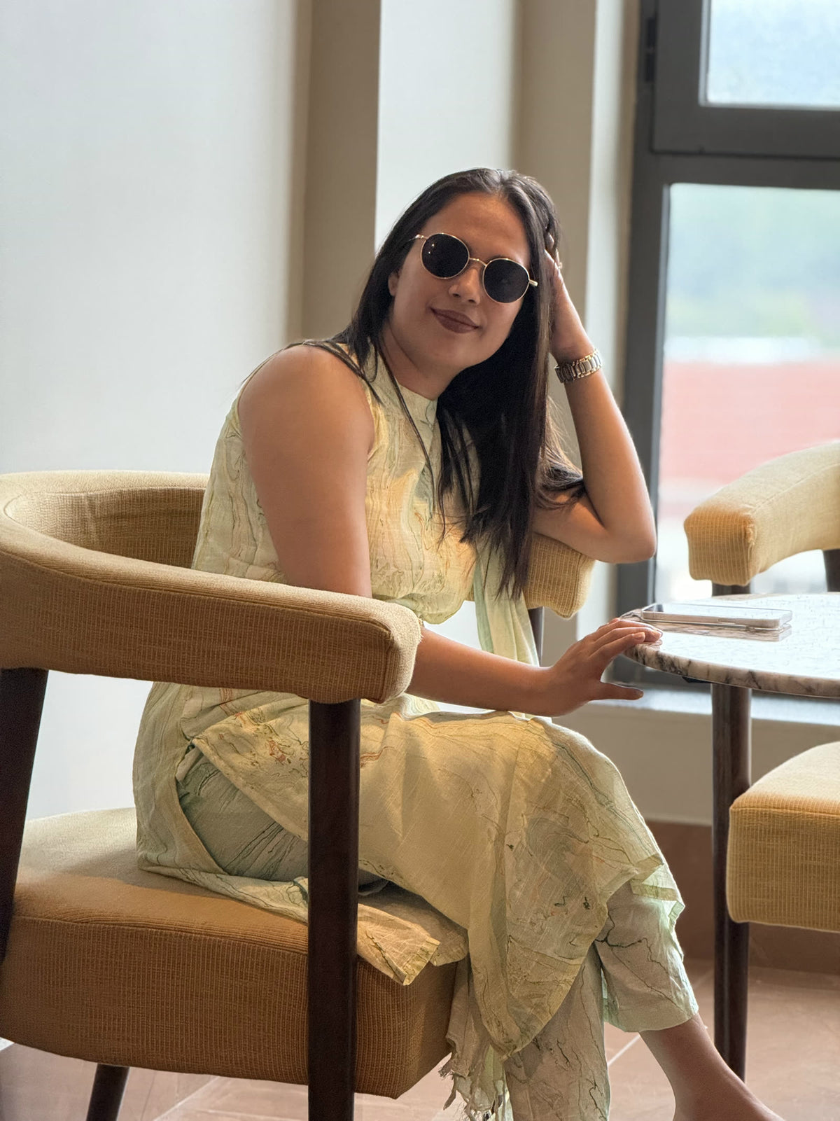 Woman in a pale green print kurta set seated in a cafe chair
